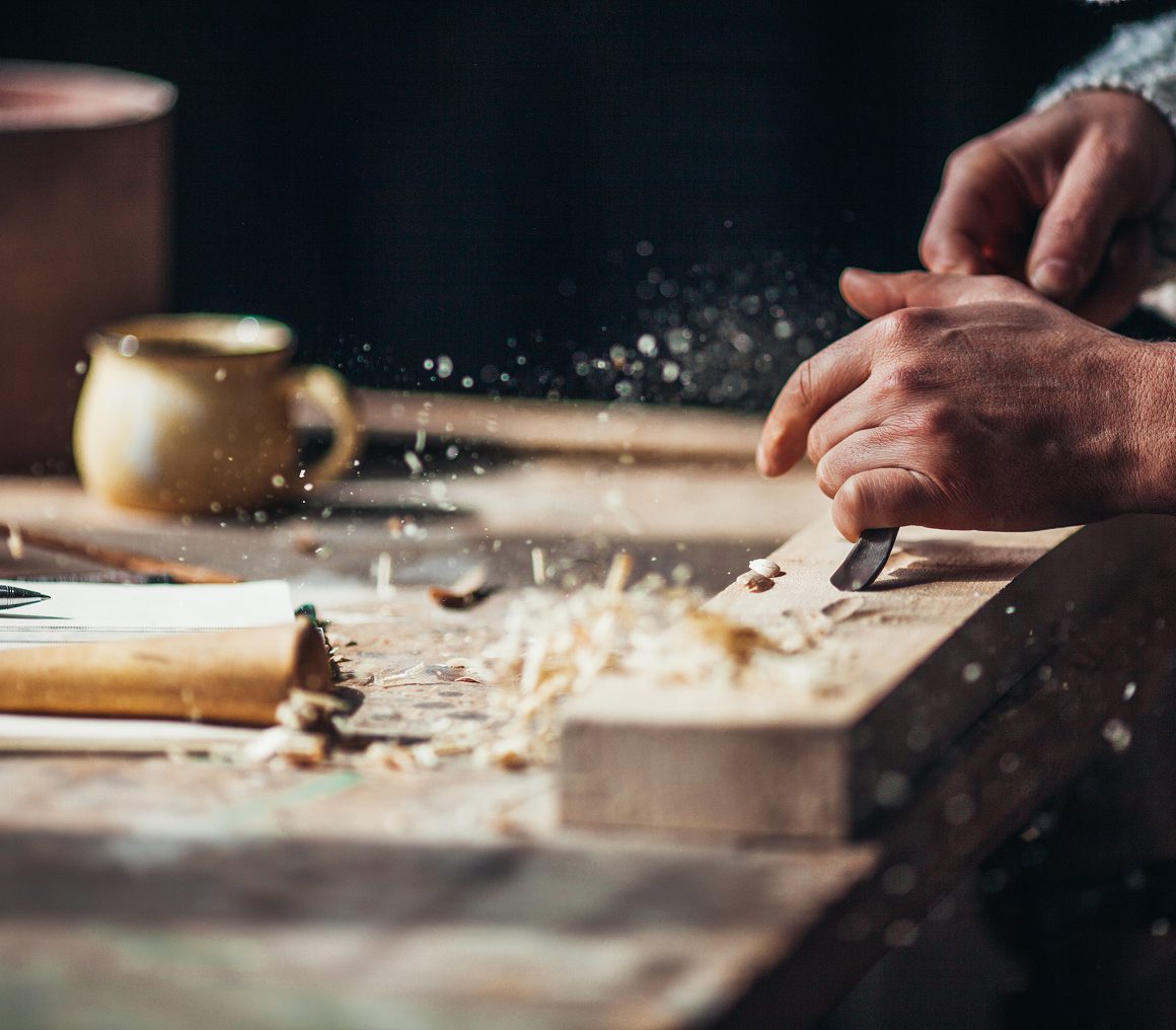 Hands carving wood on workbench